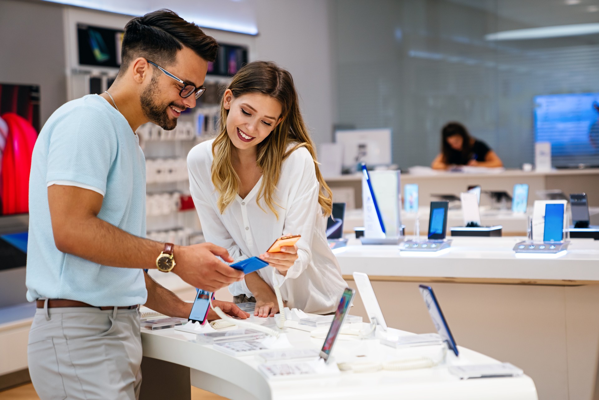 Shopping a new digital device. Happy couple buying a smartphone in store.