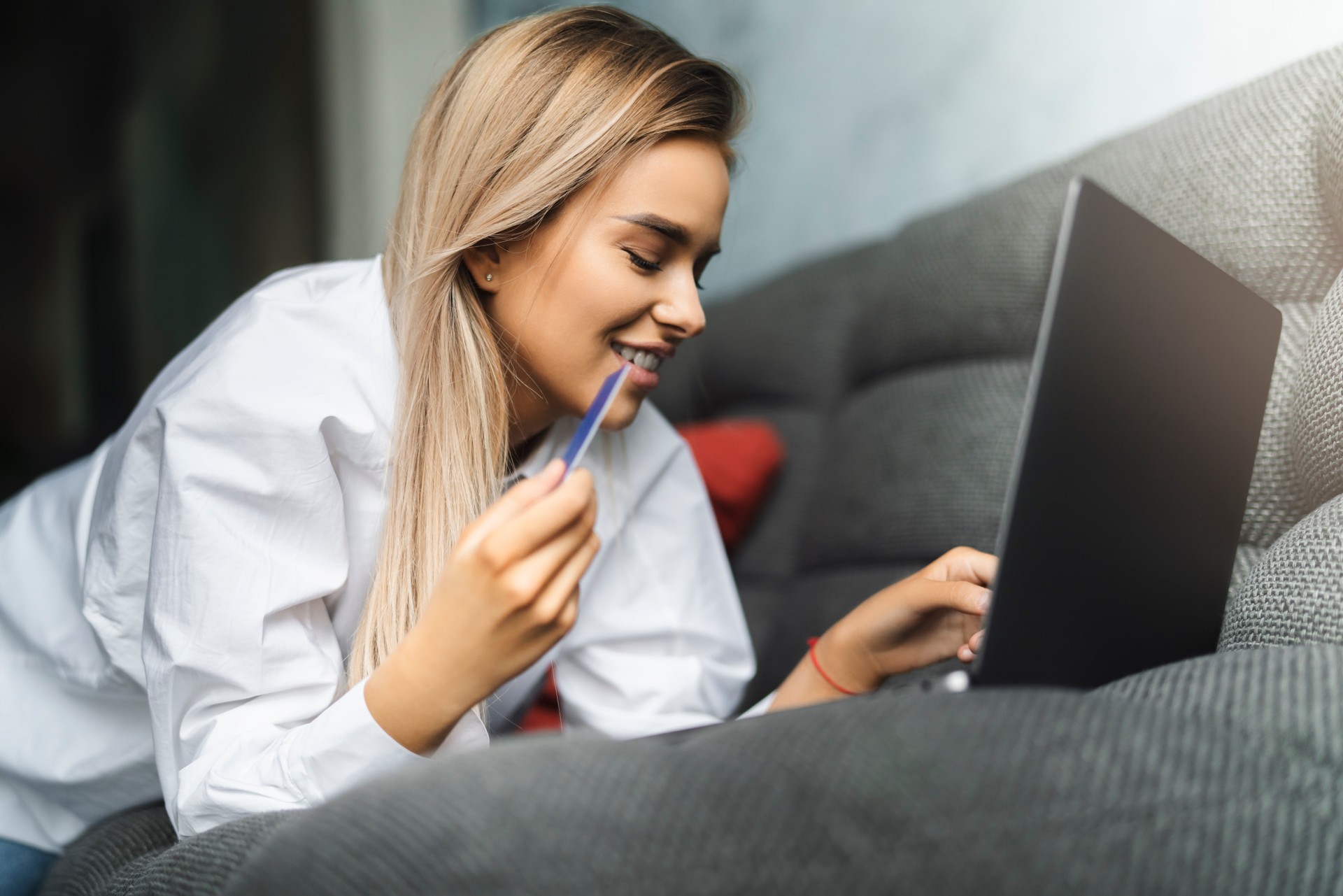 Beautiful blonde woman using bank card to pay for goods purchased online. Safe payment services for customers